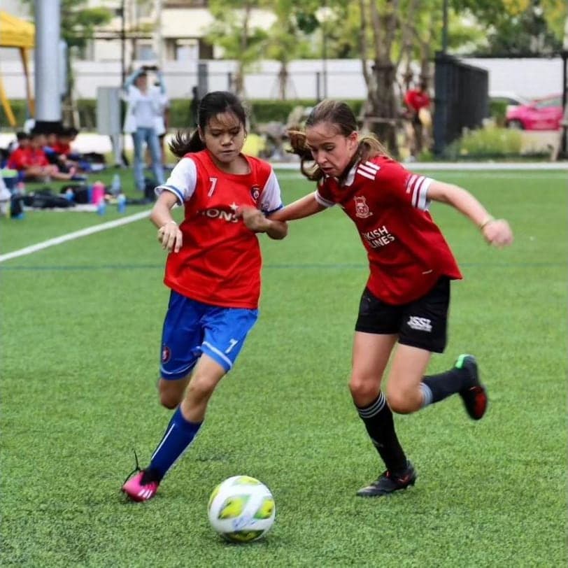 A Lions FC player running shoulder to shoulder with an opponent for the ball