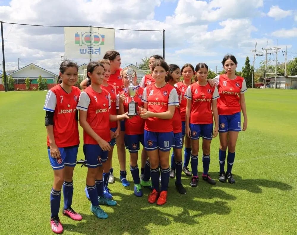 The squad holding their runners-up trophy on the pitch at Hua Hin