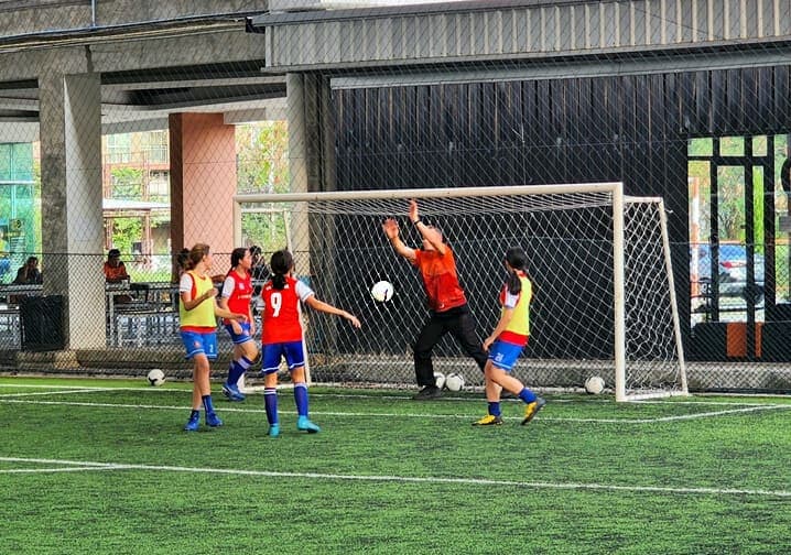 A shooting drill on the covered pitch, with the goalkeeper stretching for the ball