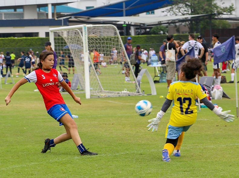 A player striking the ball past the goalkeeper during a match