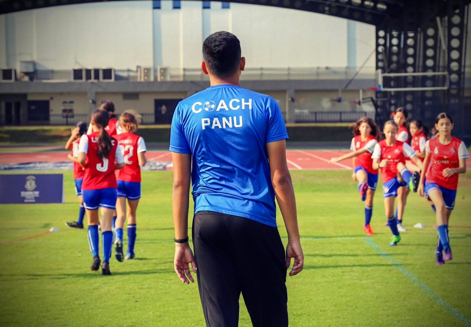 A coach leading the warm-up, the squad running the drill behind him