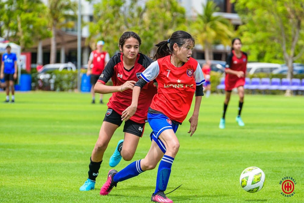 Two players running side by side with the ball during a match