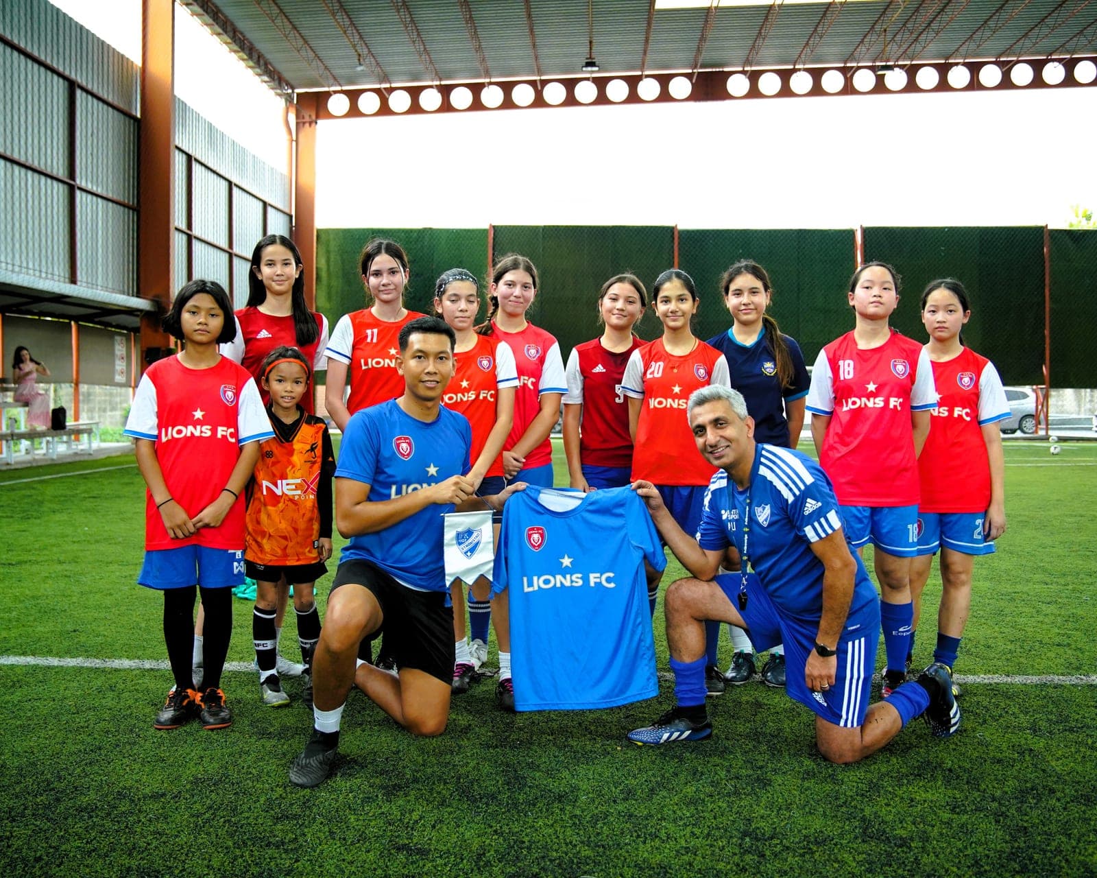 The squad with their coaches and a visiting coach, holding a club shirt