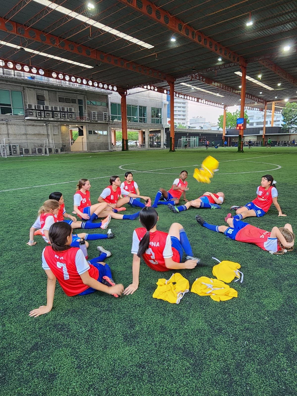 Players stretching on the pitch beside training equipment