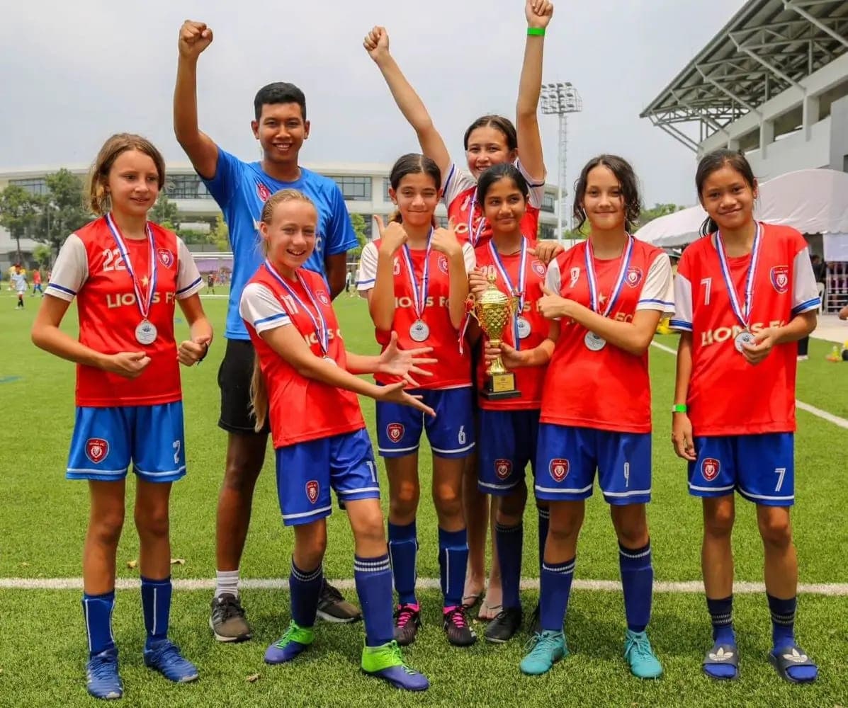 The squad celebrating with their coach, medals and cup at their first BSL tournament
