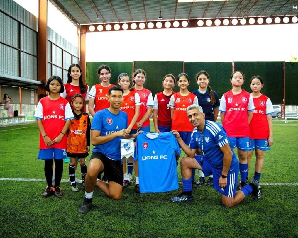 The squad with their own coach and the visiting coach from IFK Stromstad, holding a Lions FC shirt and the Swedish club pennant