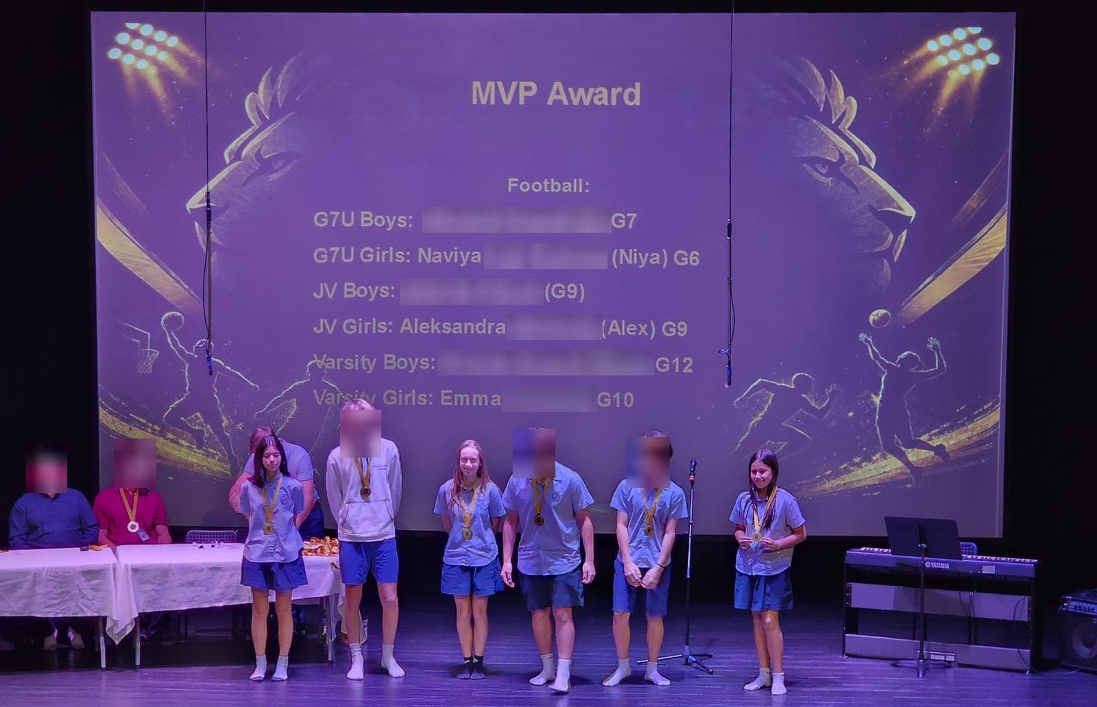 The MVP award winners on stage at Berkeley International School, the football MVP slide behind them