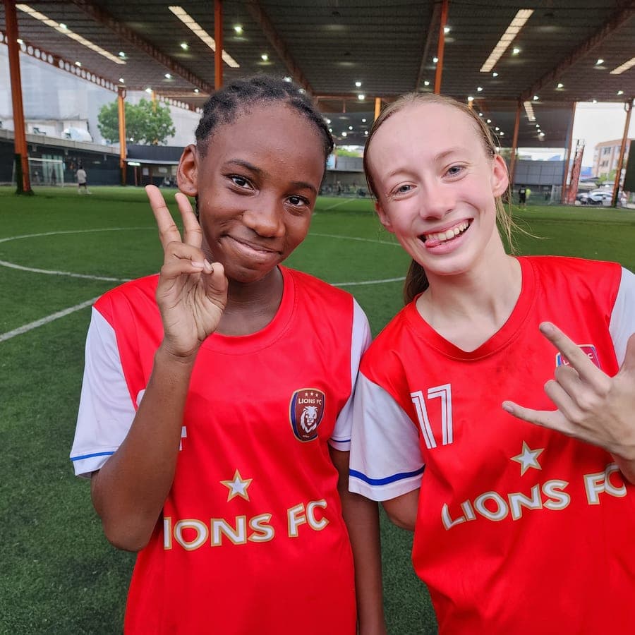 Две игроки Lions FC улыбаются в камеру после тренировки на крытом поле