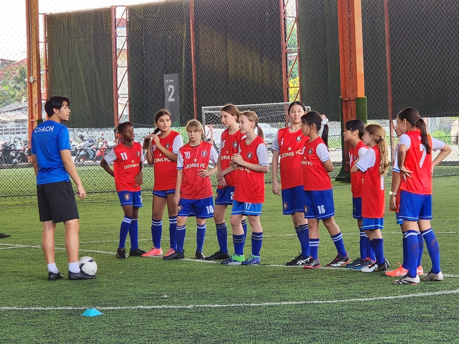 Команда Lions FC собралась вокруг тренера на крытом поле SoccerPro Bangna перед тренировкой